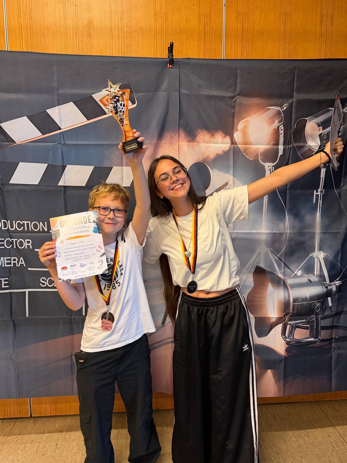 Участники Filmcamp с наградами и хлопушкой на фоне киноплаката